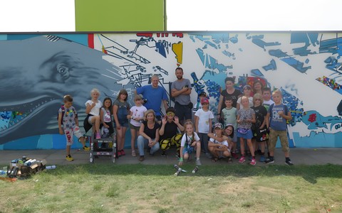 Pamiątkowe zdjęcie. Na tle muralu z Moby Dickiem stoją dzieci, które pomagały przy jego powstaniu.