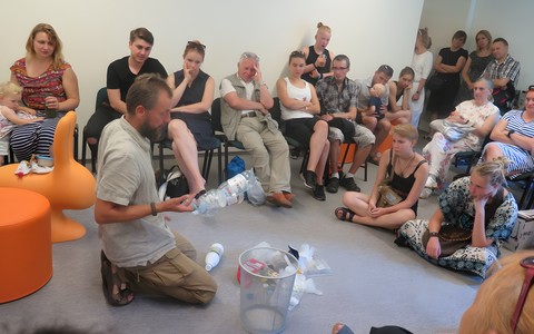 Ekoaktywista Krzysztof Beznar otoczony wianuszkiem ludzi - uczestników spotkania z jego udziałem.