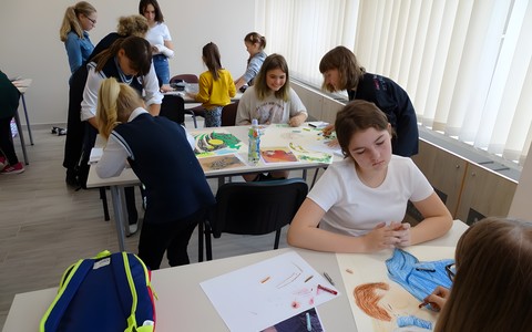 Uczestnicy Międzyszkolnego Konkursu Plastyczny z cyklu Malujemy jak Matejko siedzą przy stołach i malują kopie obrazów Stanisława Wyspiańskiego.