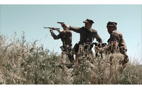 Na zdjęciu: Kadr z filmu „KOMAR. Partyzant w US Army". Widać trzech uzbrojonych żołnierzy na łące