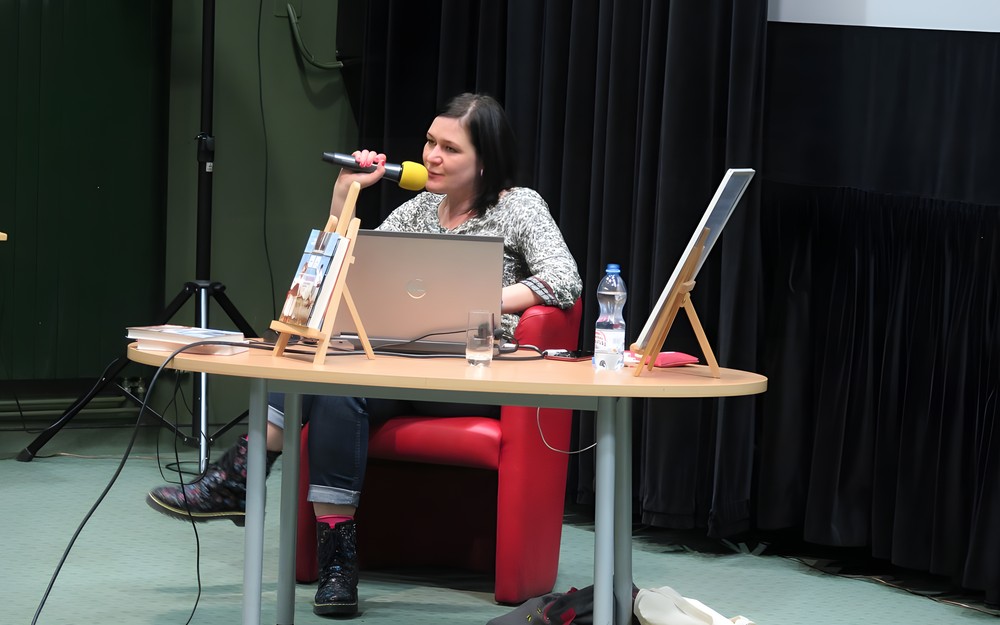 Stasia Budzisz siedzi przy stoliku podczas spotkania. Przed nią stoi laptop