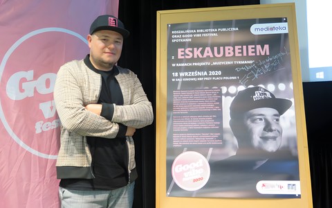 Bartłomiej Skubisz stoi na scenie obok plakatu promującego wydarzenie