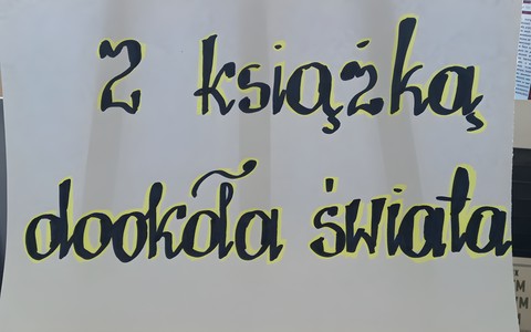 Biała kartka z czarno-żółtym napisem: Z książka dookoła świata