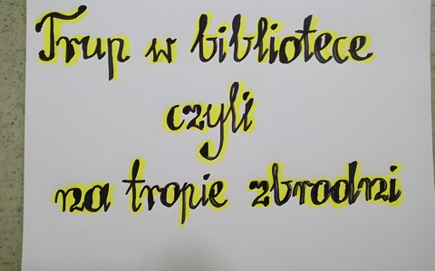 Biała kartka z czarno-żółtym napisem: Trup w bibliotece, czyli na tropie zbrodni.