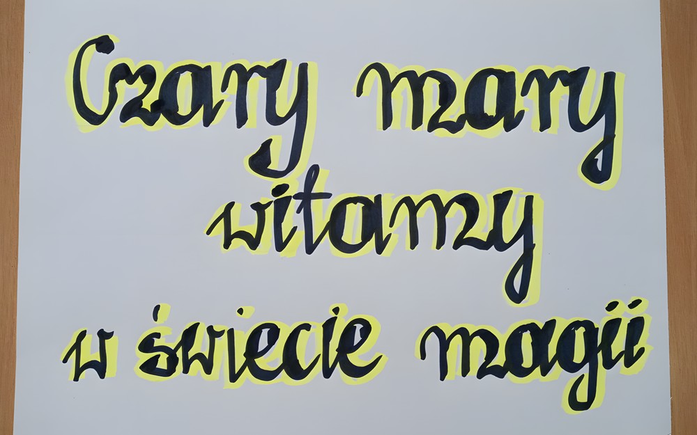 Biała kartka z czarno-zółtym napisem: Czary mary - witamy w świecie magii.