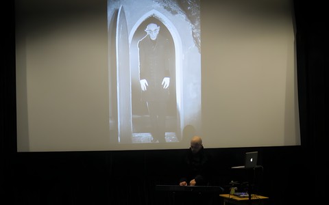 Maciej Trembowiecki podczas swojego koncertu. W tle prezentacja zdjęcia z filmu "Nosferatu"