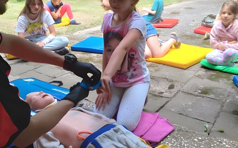 Ratownik medyczny uczy na fantomie grupę uczestników zajęć jak udzielać pierwszej pomocy