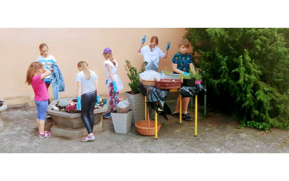 Grupa dzieci sadząca rośliny w gazonie