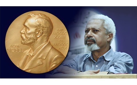 Po lewej stronie grafiki znajduje się wizerunek medalu noblowskiego. Po prawej zdjęcie portretowe Abdulrazaka Gurnaha (Gurnah w maju 2009, autor fot. Liftarn, licencja CC BY 2.0)