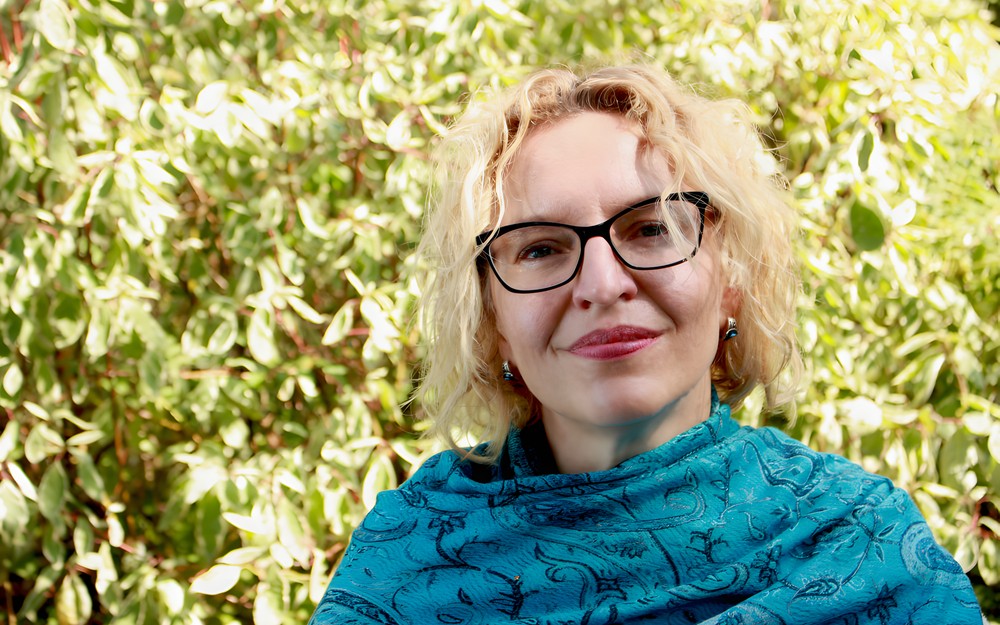 Fotografia Joanny Jagiełło na tle zieleni drzewa