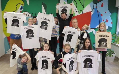 Grupowe zdjęcie dzieci z koszulkami i torbami.