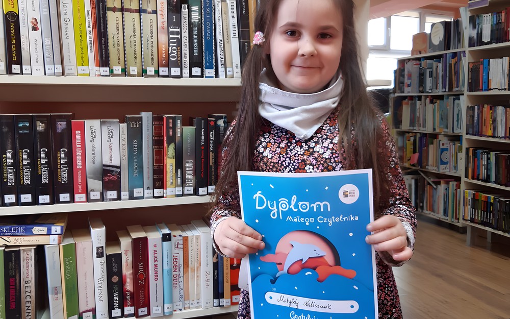 Na zdjęciu dziewczynka biorąca udział w akcji #MałaKsiążkaWielkiCzłowiek