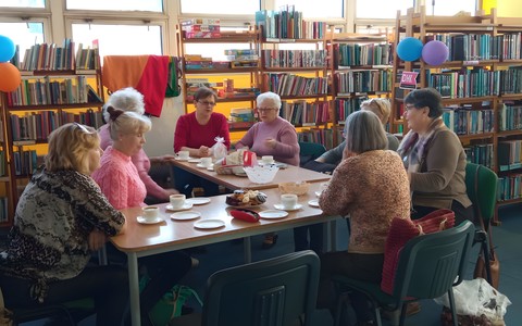 Panie siedzą przy stolikach i rozmawiają o wielkanocnych ozdobach.