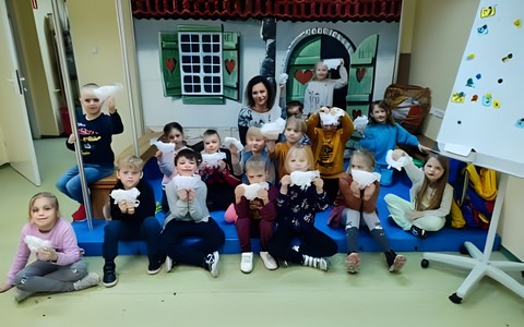 Dzieci wraz z bibliotekarką prezentują swoje prace plastyczne