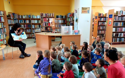 Pani Wiola prezentuje siedzącym na chuście animacyjnej przedszkolakom najpiękniejsze książki dla maluchów