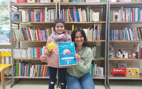 Dziewczynka z bibliotekarką prezentują dyplom