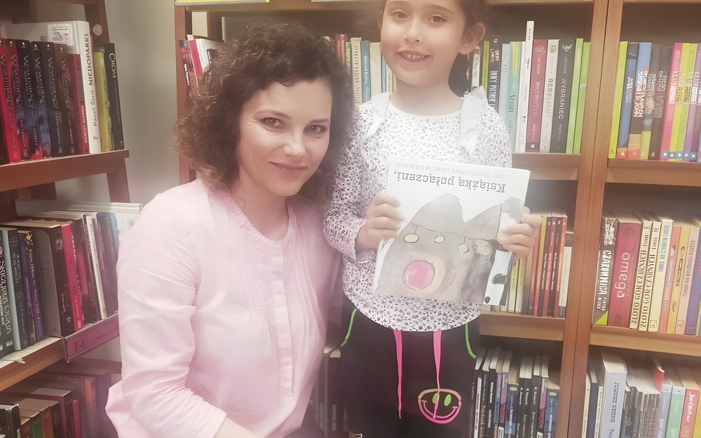 Dziewczynka z bibliotekarką prezentują książeczkę