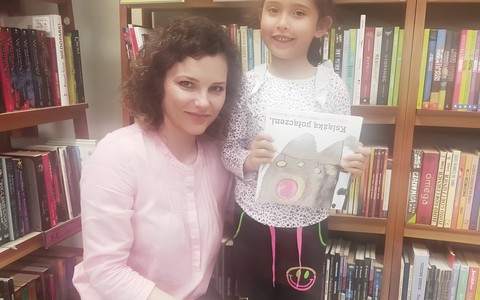 Dziewczynka z bibliotekarką prezentują książeczkę
