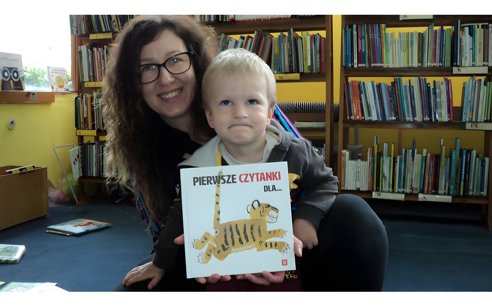 Mama i synek pozują do zdjęcia z książką