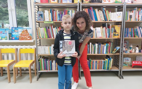 Chłopiec pozuje z książeczką i bibliotekarką