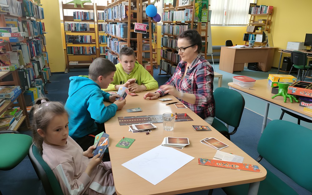 bibliotekarka gra z dziećmi w grę planszową