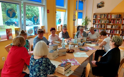 Czytelniczki siedzą przy stołach, na których rozłożone są nowości książkowe - rozpoczynamy spotkanie