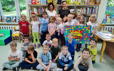 Bibliotekarki i dzieci pozują z plakatem przyjaźni
