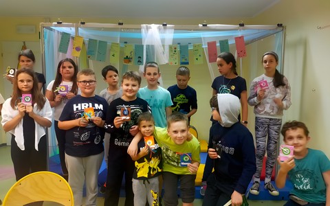 Dzieci stoją na scenie i prezentują swoje prace