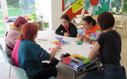 Młodzież z Ukrainy gra w Blokusa z bibliotekarką Kasią.