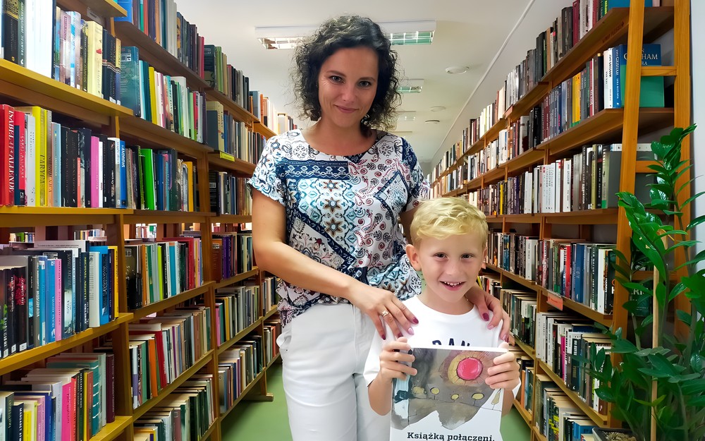 Dziecko z bibliotekarką prezentują książeczkę