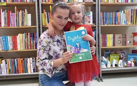 Dziewczynka i bibliotekarka prezentują dyplom