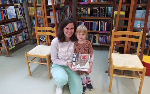 Dziewczynka i bibliotekarka prezentują książkę