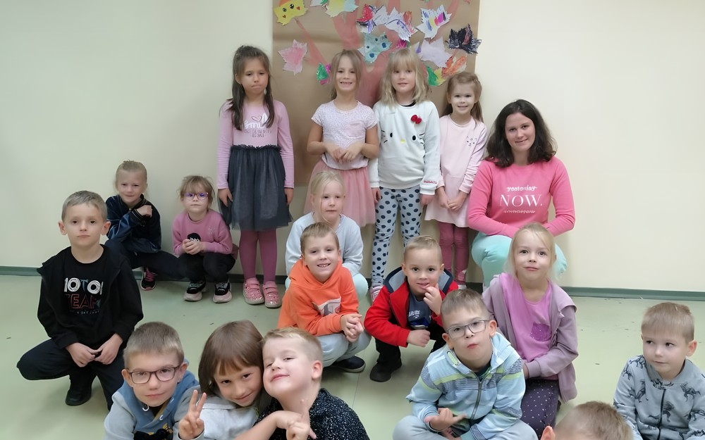 Dzieci wraz z bibliotekarką stoją i prezentują swoje prace