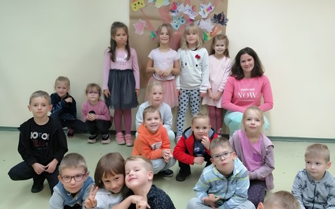 Dzieci wraz z bibliotekarką stoją i prezentują swoje prace