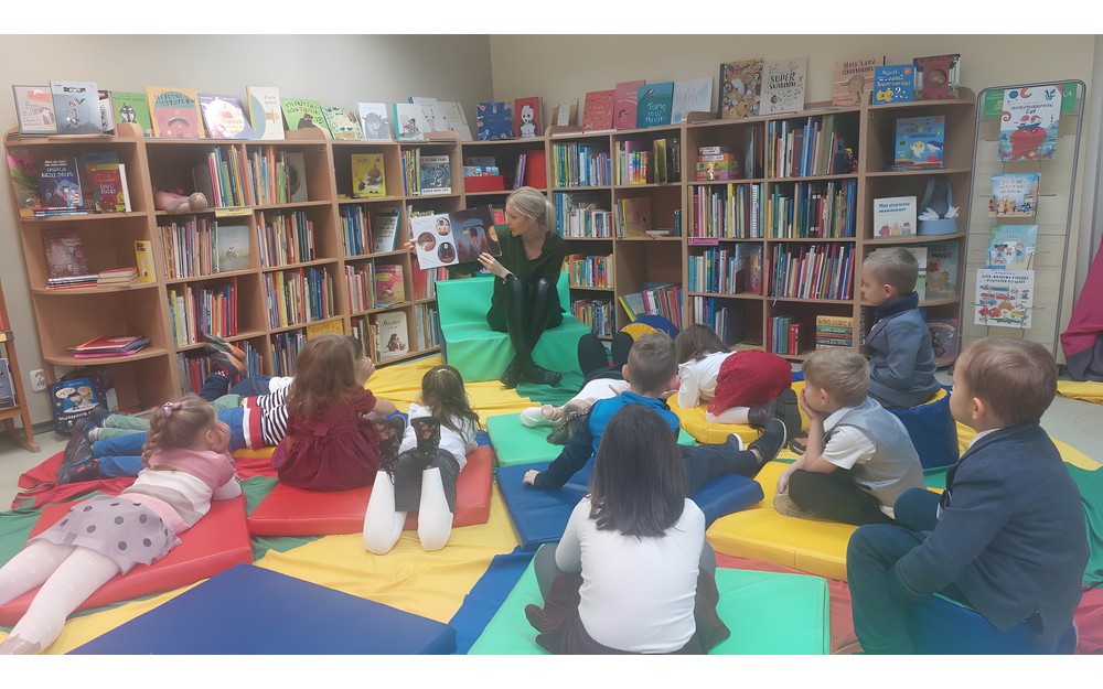 Dzieci słuchają opowiadania, które czyta im bibliotekarka