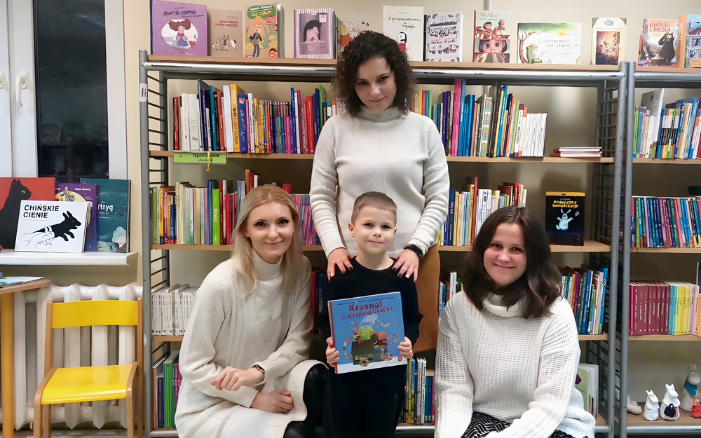 Jurek w towarzystwie trzech bibliotekarek pozuje do zdjęcia z książeczką