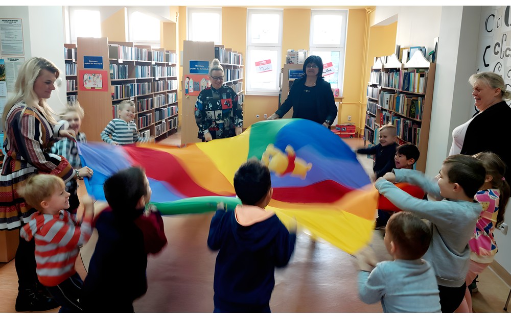 Przedszkolaki z grupy MOTYLKÓW usypiają pluszowego misia, kołysząc chustą animacyjną