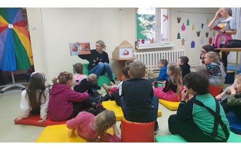 Dzieci słuchają opowiadania czytanego przez bibliotekarkę