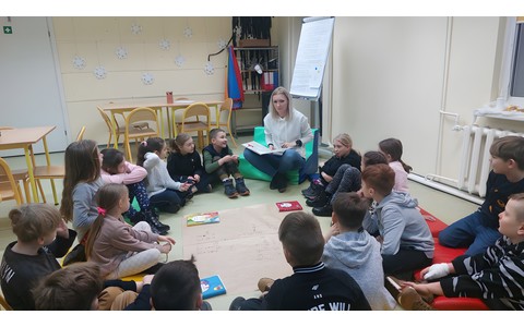 Dzieci słuchają opowiadania, które czyta im bibliotekarka