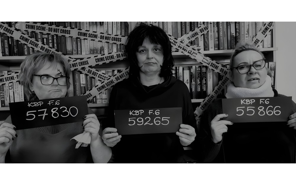 Na zdjęciu Gosia, Wiola i Ewa stoją na tle regałów z kryminałami, trzymając tabliczki z numerami inwentarzowymi popularnych kryminałów