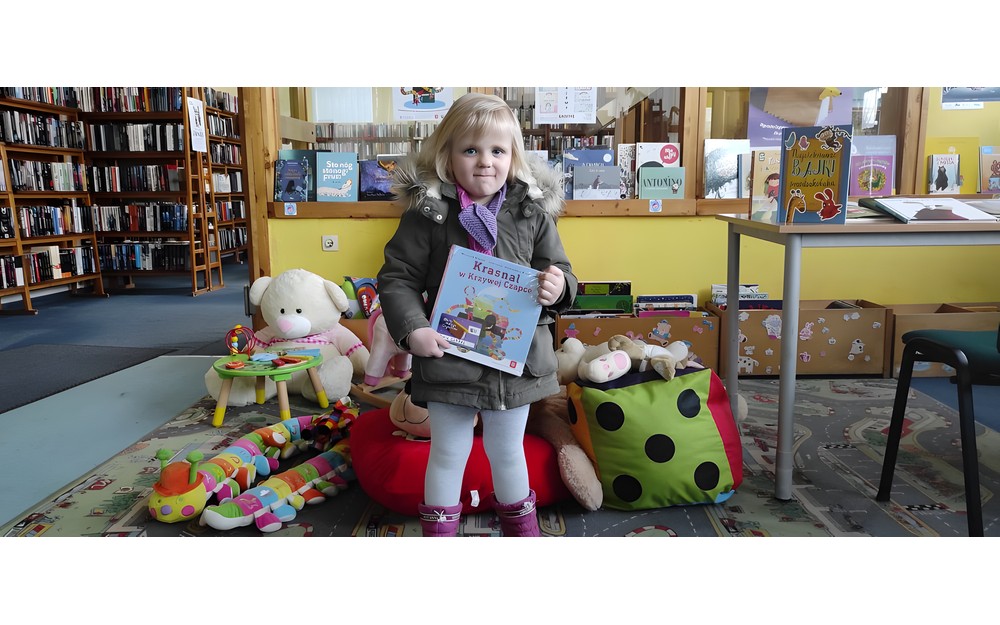 dziewczynka pozuje do zdjęcia z pakietem "Mała książka, Wielki człowiek"