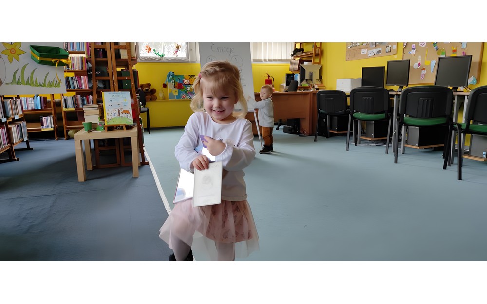 dziewczynka pozuje do zdjęcia z pakietem "Mała książka, Wielki człowiek"