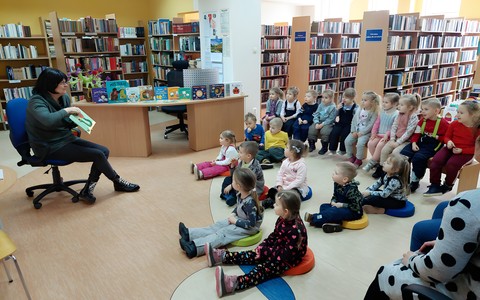 Na zdjęciu Wiola prezentuje dzieciom siędzącym na podłodze, książkę pt. Wszyscy ziewają