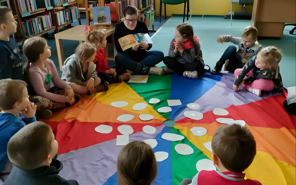 bibliotekarka czyta opowiadanie, dzieciom siedzącym na chuście