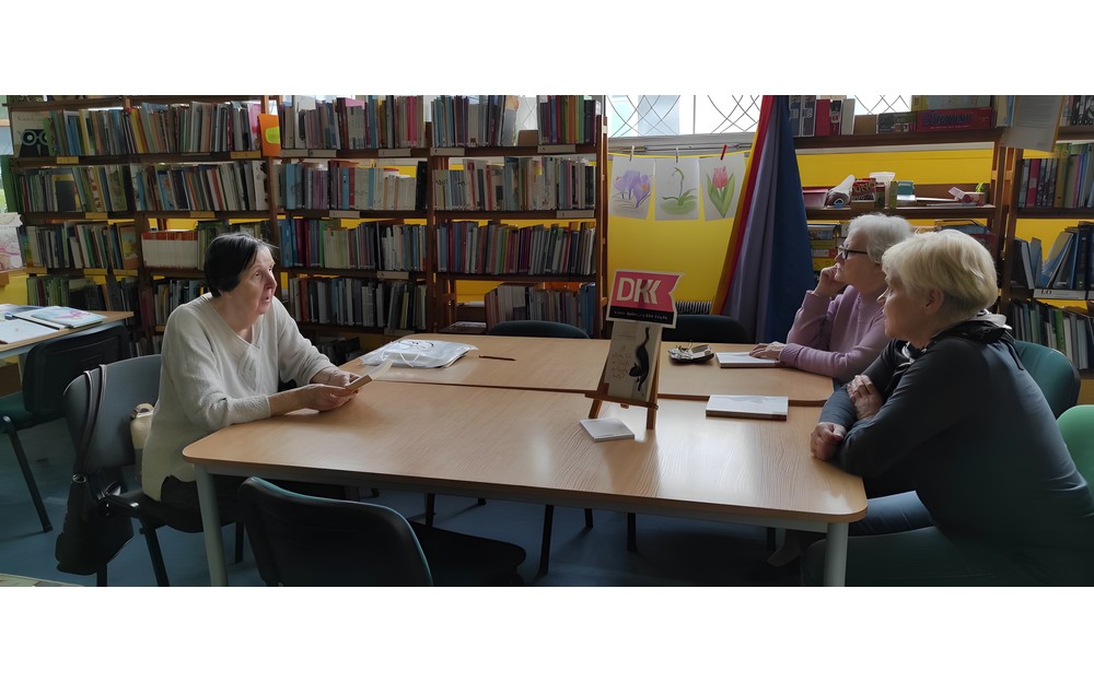 trzy panie dyskutują o książce siedząc przy stole