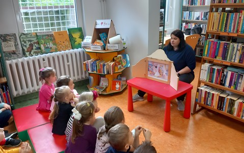 Bibliotekarka czyta dzieciom teatrzyk kamishibai.