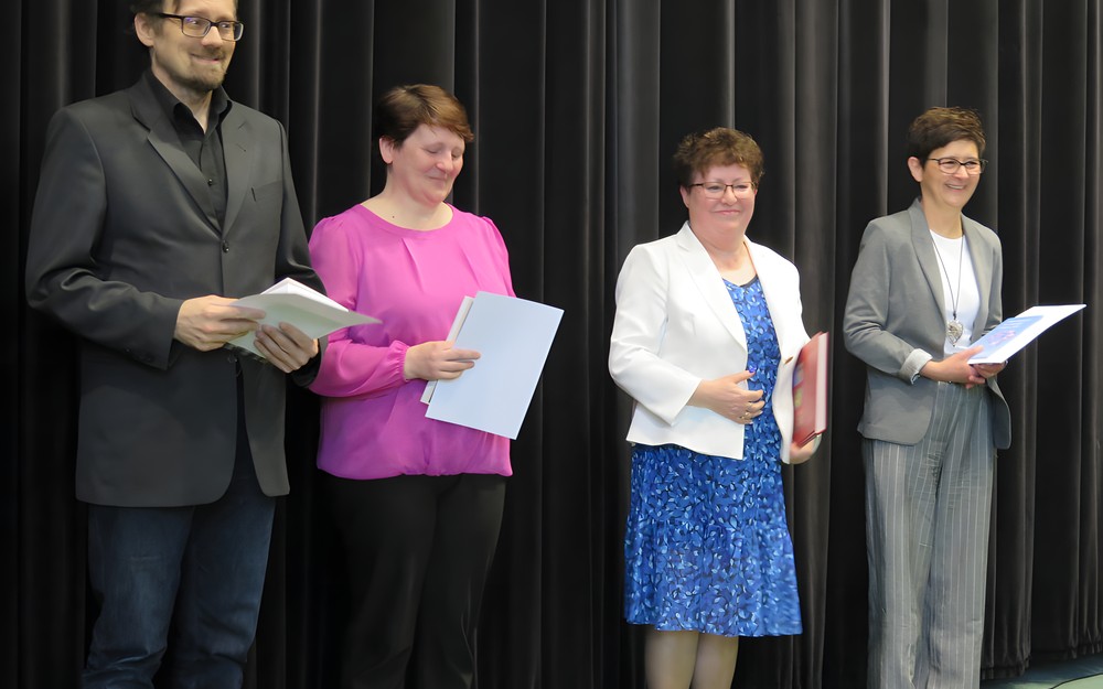 Jubilaci stoją na scenie w czasie Dnia Bibliotekarza w Koszalińskiej Bibliotece Publicznej