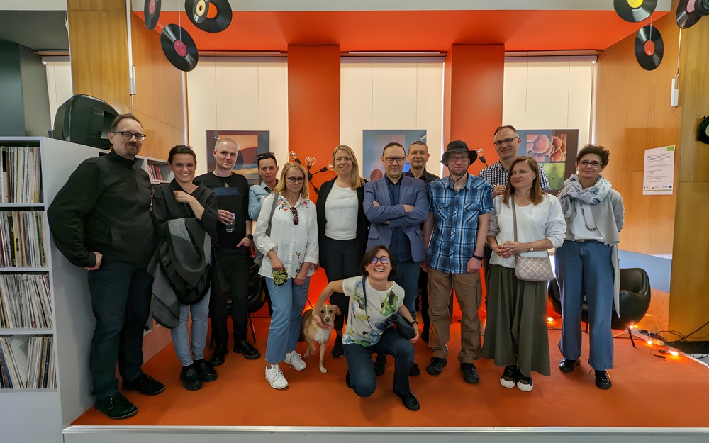 Zdjęcie przedstawia uczestników wernisażu wraz z Mariuszem Weltrowskim na scenie Mediateki KBP