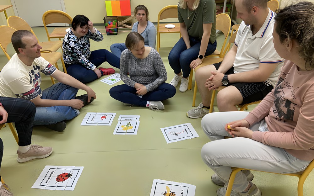 Uczestnicy spotkania układają puzzle z wiosennymi motywami