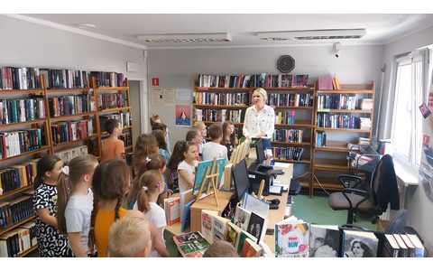Bibliotekarka oprowadza grupę uczniów po bibliotece